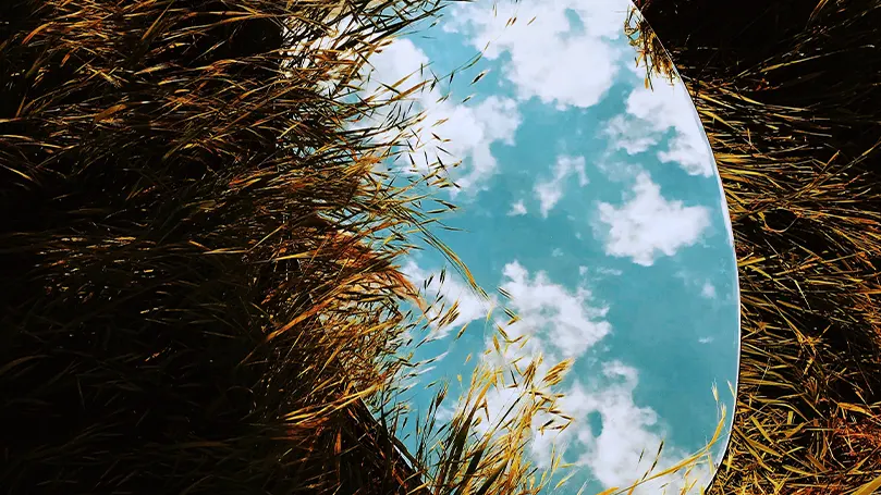 Uma imagem de um espelho colocado no chão que reflecte o céu