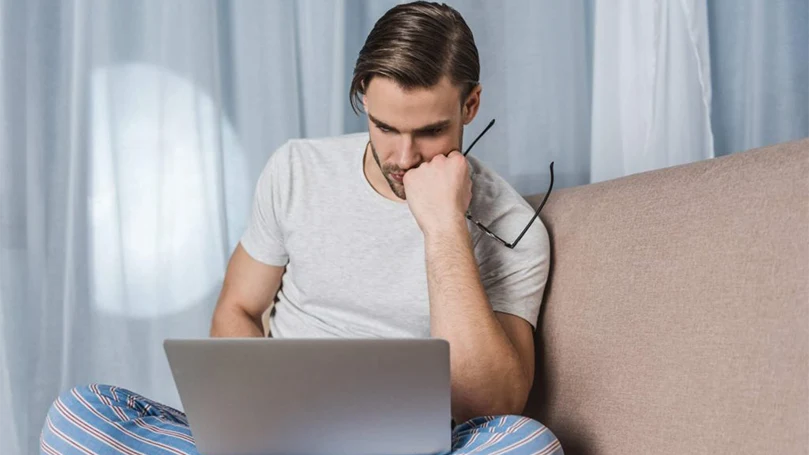 um homem a trabalhar até tarde da noite em frente a um computador portátil