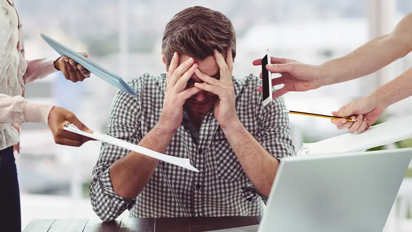 Uma imagem de um homem a ser dominado por pessoas que colocam papéis e telemóveis perto da sua cabeça