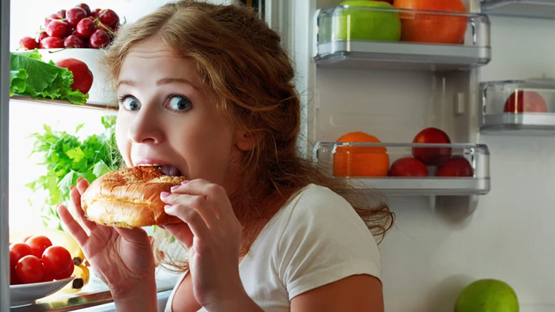 uma imagem de uma mulher a comer um lanche noturno