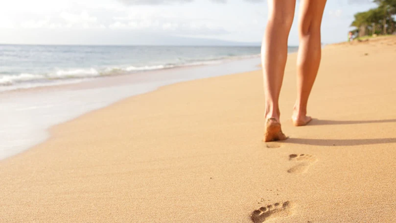 uma mulher a caminhar na praia