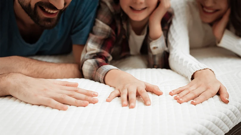 an image of a happy family laying on a mattress