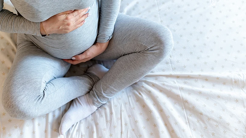 uma mulher grávida que segura o seu estômago