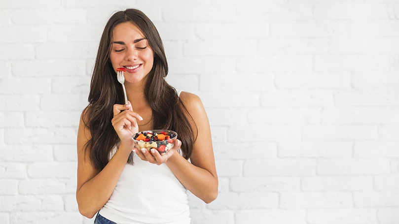 uma imagem de uma jovem mulher a comer alimentos saudáveis para recordar os sonhos