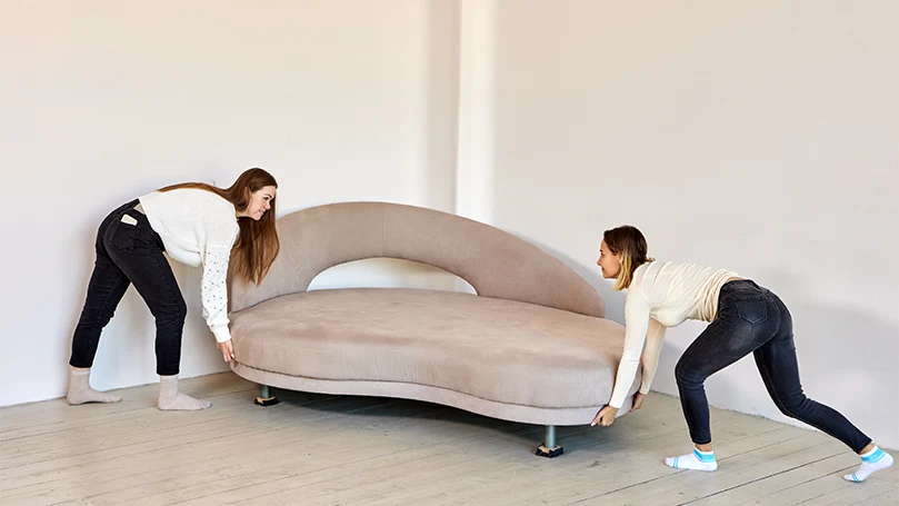 an image oftwo women carrying a divan bed