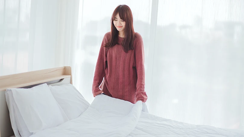 an image of a woman arranges bed and changes sheets