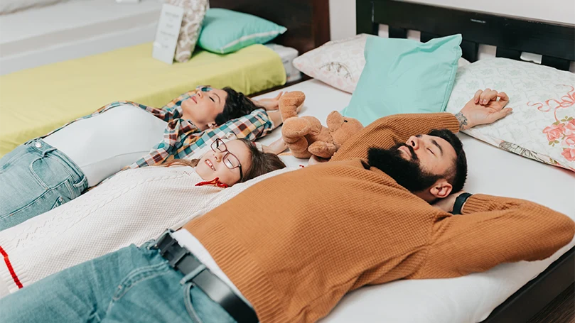 An image of a young family laying down on a gel topped mattress.