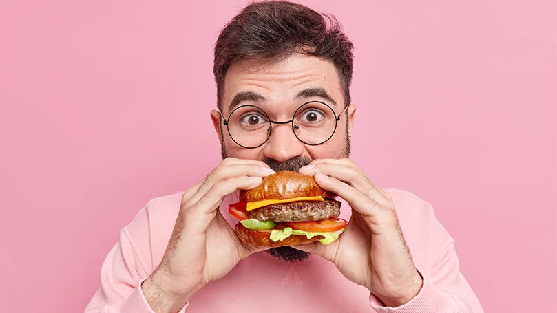 Uma imagem de um homem a comer um hambúrguer.