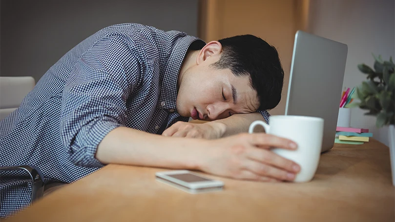 Uma imagem de um homem adormecido no seu escritório.