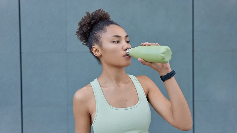 Uma imagem de uma jovem mulher a beber água durante o treino.