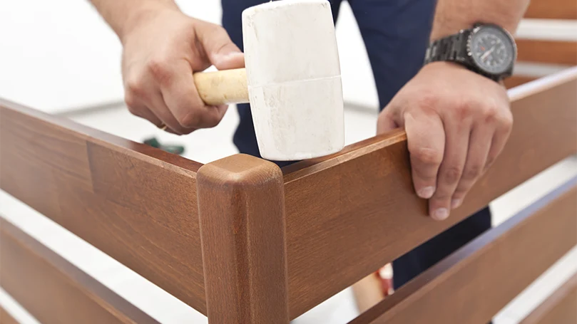 An image if a man assembling box spring and checking if it is squeaking.