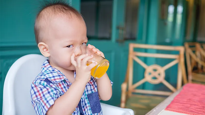 Uma imagem de um bebé de 18 meses a beber sumo.