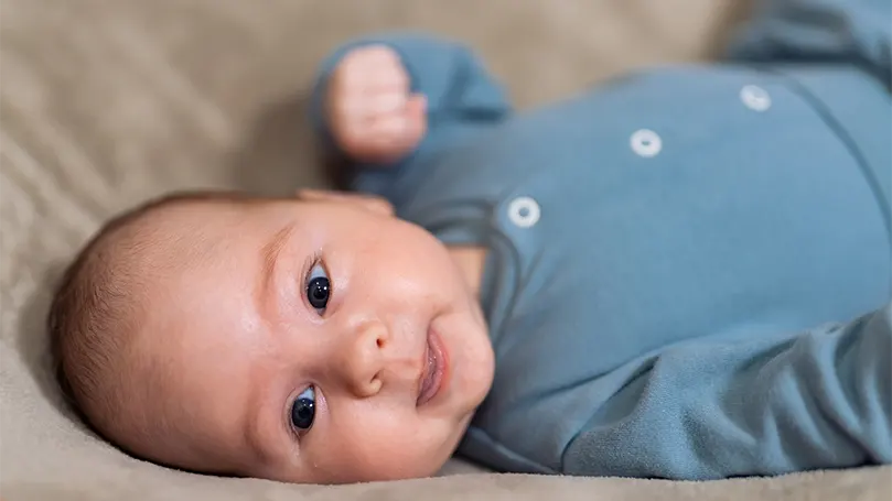 An image of 2 month old baby laying on its back.