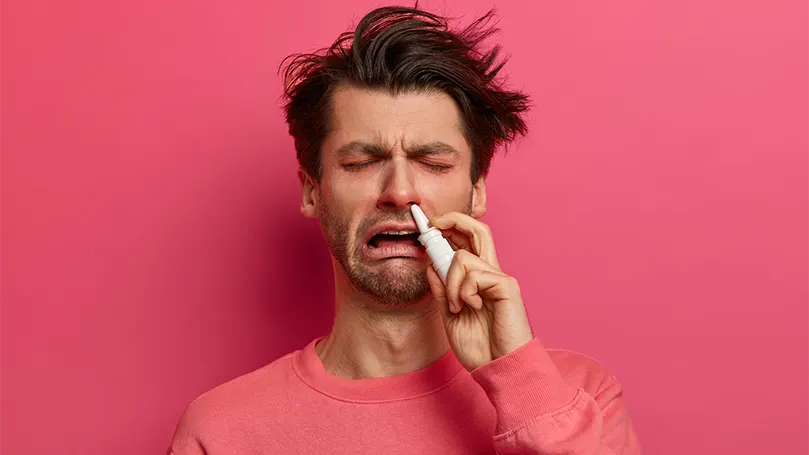 Imagem de um homem que sofre de alergias e utiliza gotas nasais.