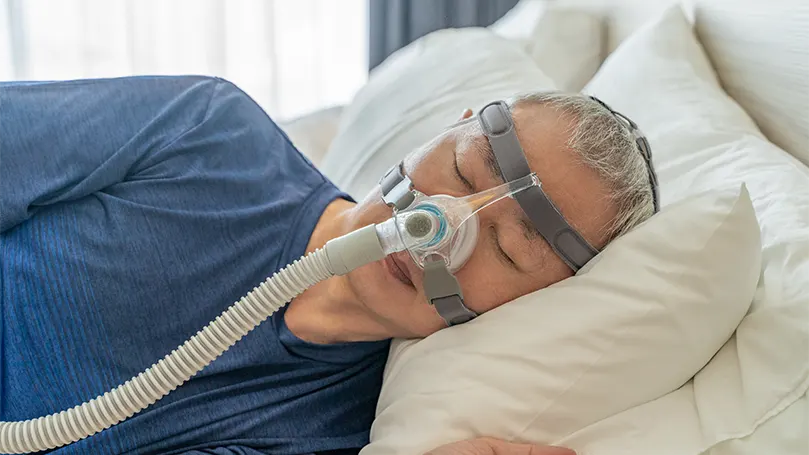 Um homem idoso a dormir com uma máscara CPAP