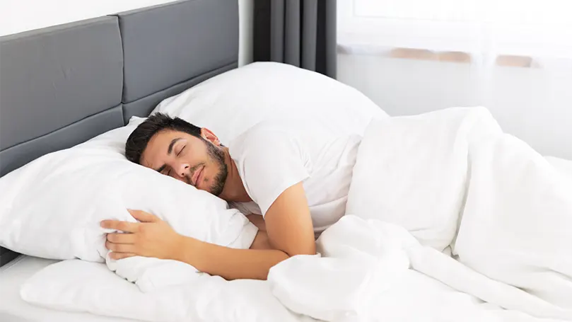 An image of a young man sleeping with head pointing towards south.