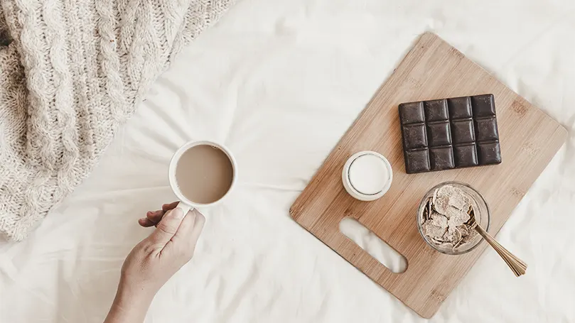 Uma mão a segurar uma chávena de chocolate quente.