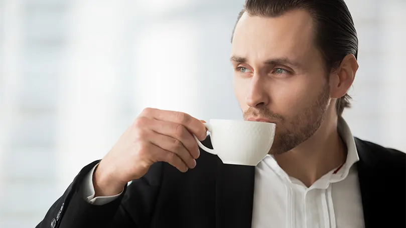 Uma imagem de um homem a beber café e a sonhar acordado.