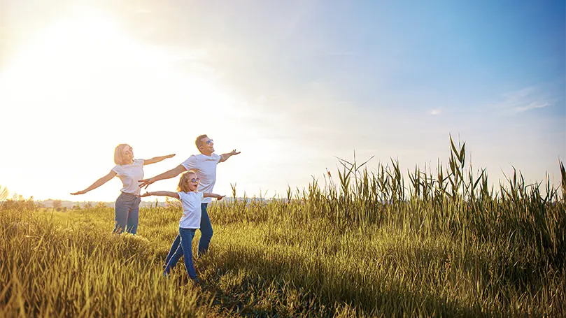 Uma imagem de uma família no exterior a correr num campo