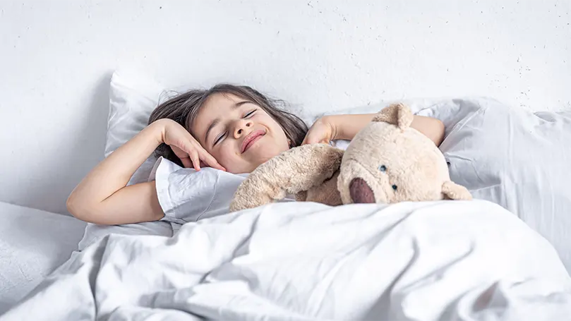 a-girl-sleeping-with-a-teddy-bear-in-bed