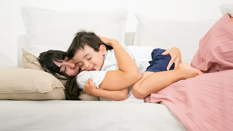 An image of a mom on a couch with an infant.