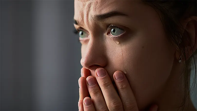 Uma imagem de uma mulher triste com olhos verdes a chorar.