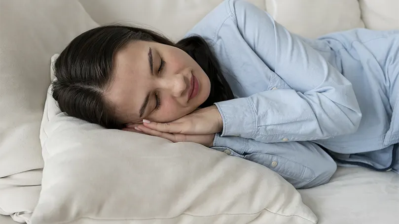 Uma imagem de uma mulher a dormir num sofá com um espaço limitado.