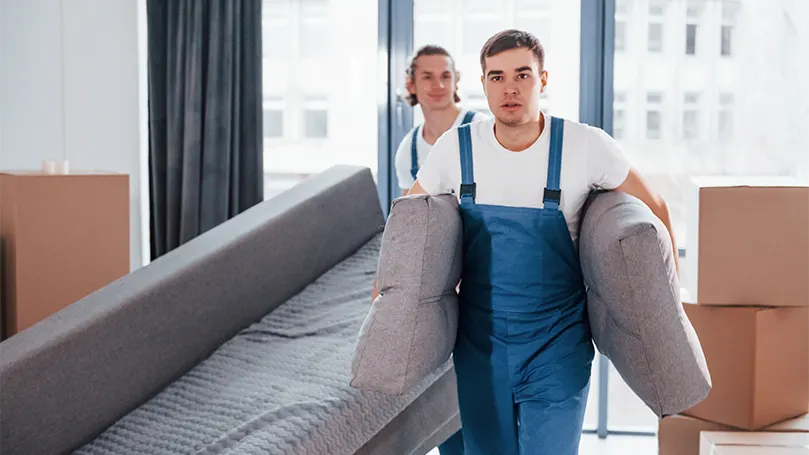 Uma imagem de dois homens de uma empresa profissional a transportar uma cama.