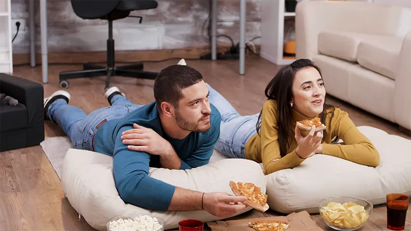 Uma imagem de um casal no chão a comer piza.