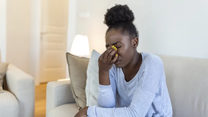 Uma imagem de uma jovem mulher negra a sofrer de fadiga ocular,