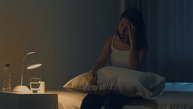 An image of a woman in bed at night unable to sleep due to a lack of melatonin