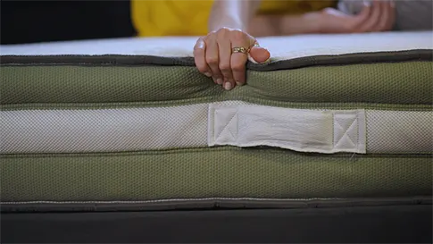 Connie squeezing the edge of the mattress while laying on it