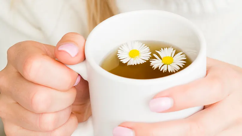 An image of a person holding a cup of tea in order to fall asleep more easily