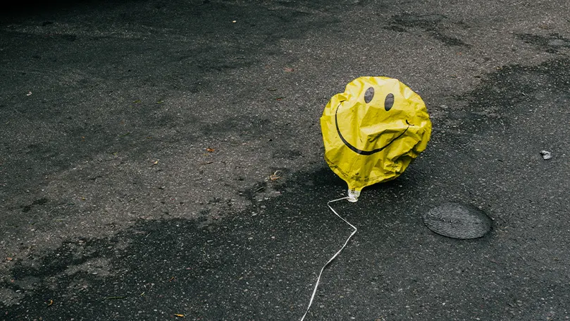 Uma imagem de um balão esvaziado com um smiley