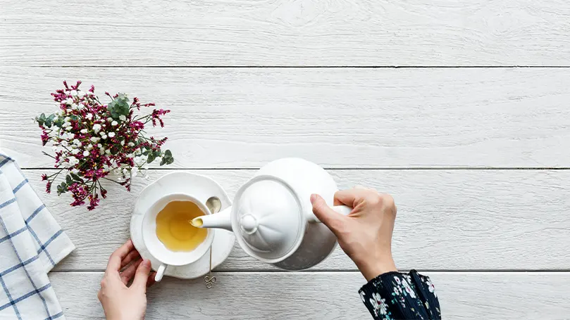 An image of a person pouring white tea into their cup