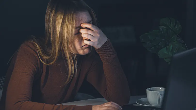 An image of a woman with anxiety at night holding her face with her hand