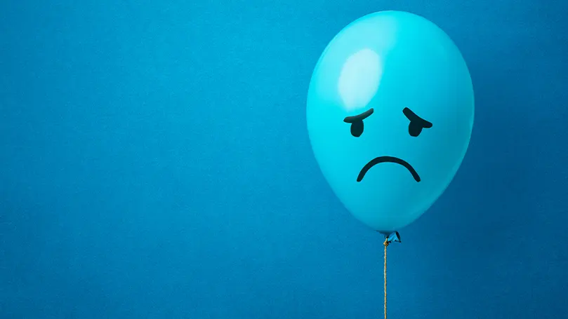 Uma imagem de um balão azul com uma cara triste desenhada