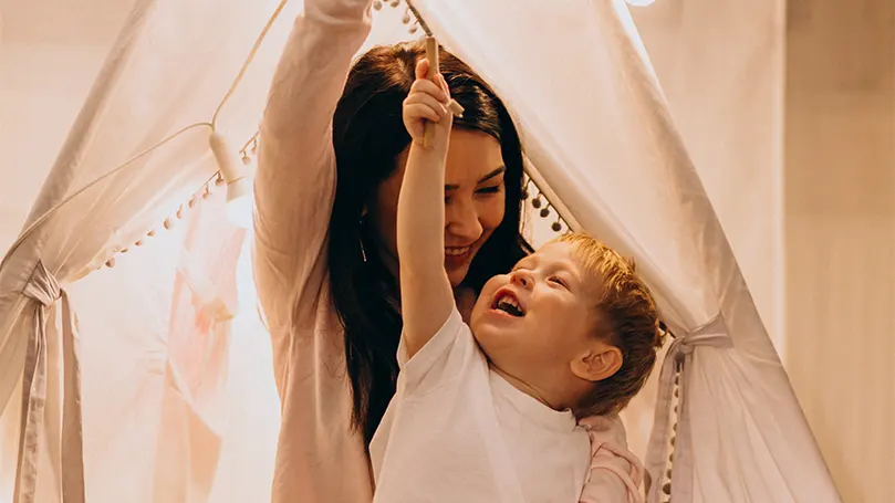 An image of a woman under a blanket fort with her child