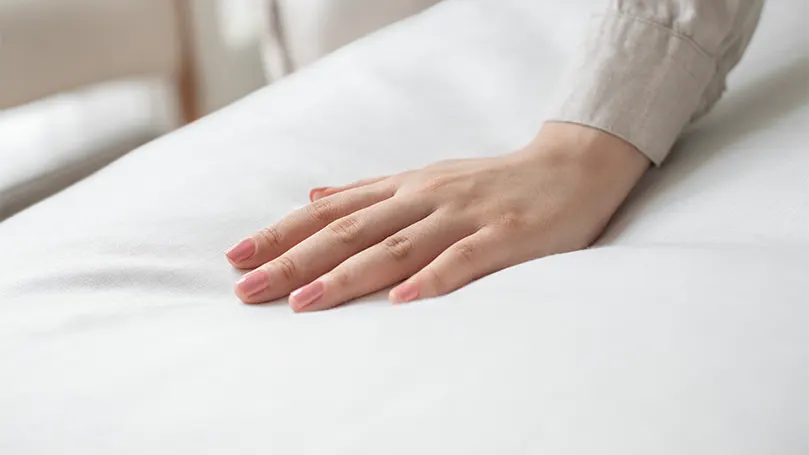 An image of a custom mattress being pressed by a hand