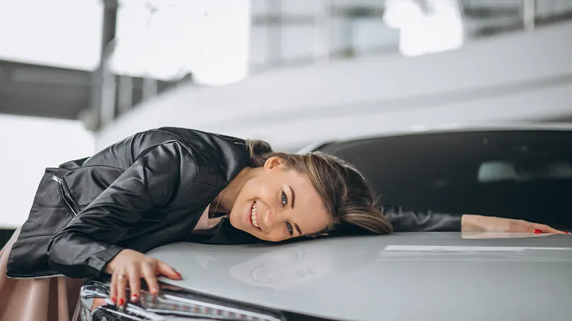 An image of a woman laying on the hood of the car.