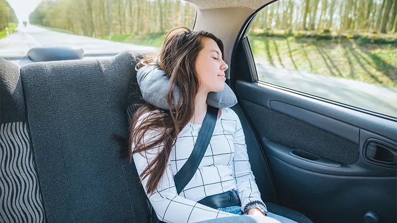 Uma imagem de uma mulher a dormir num carro.