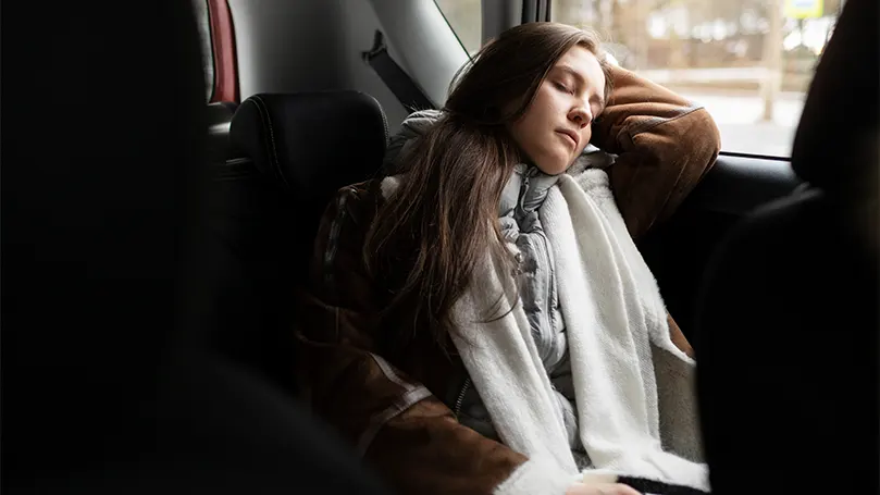 Uma imagem de uma mulher a dormir no seu carro