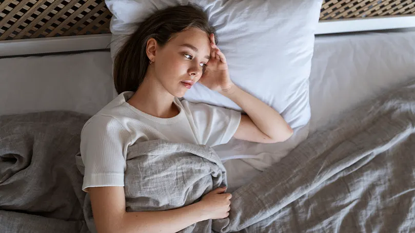 A woman laying down in bed while being hot