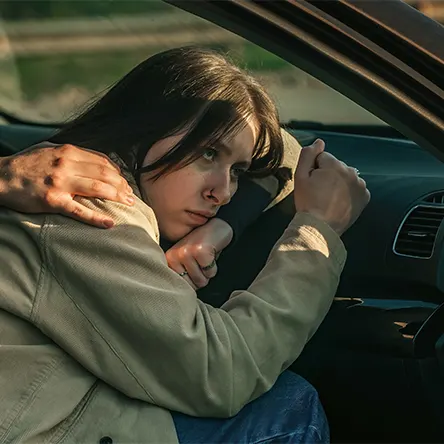 An image of a woman sleeping in her car.