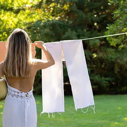 Uma mulher pendura roupa para secar ao ar livre