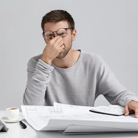 Um homem cansado, de óculos, sentado à mesa