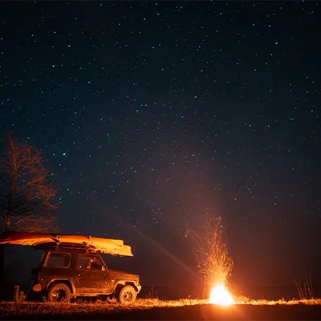 Uma imagem de uma fogueira junto a uma carrinha à noite