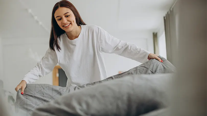 A woman setting up her bed