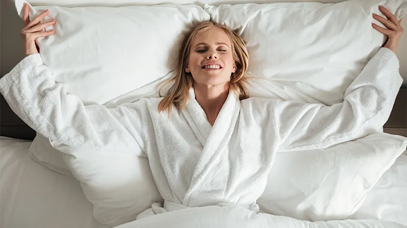 Uma mulher de roupão de banho deitada na cama