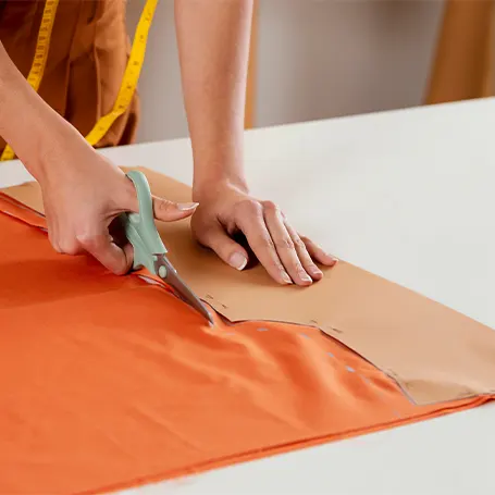 An image of a seamstress measuring and cutting fabric.